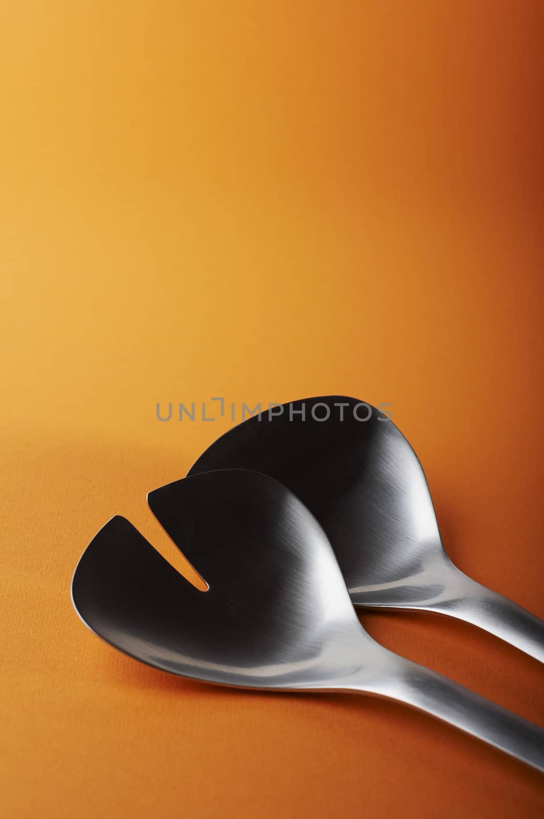 big salad spoon and fork on orange background