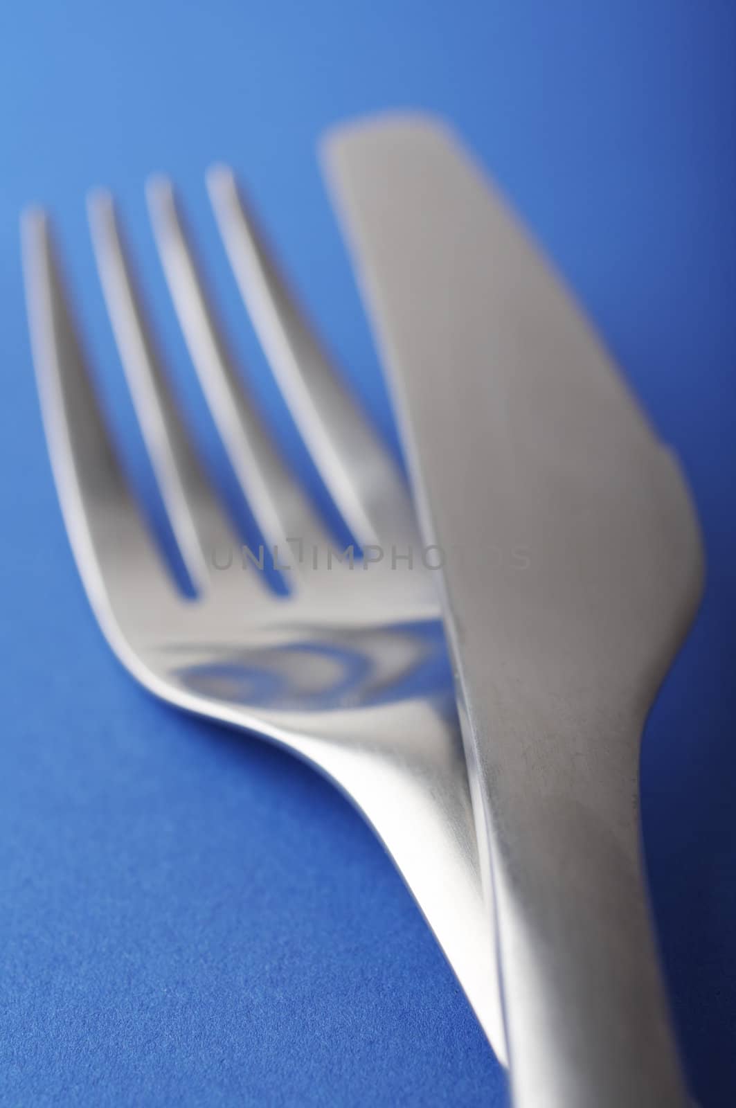 close up of a fork and spoon on blue background