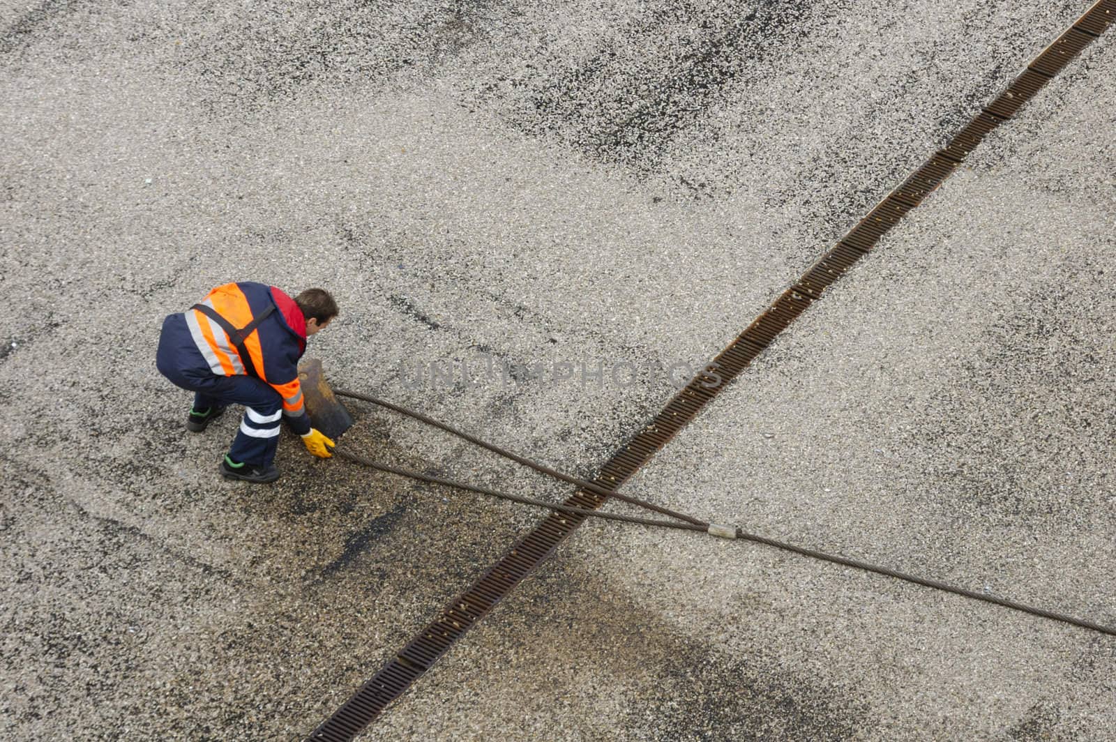 On the dockside a worjker casts off the mooring cable of a ship.