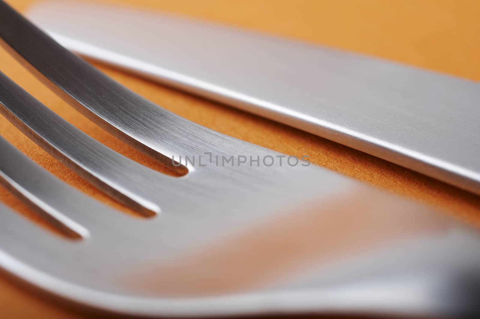 close up of fork and knife on orange background