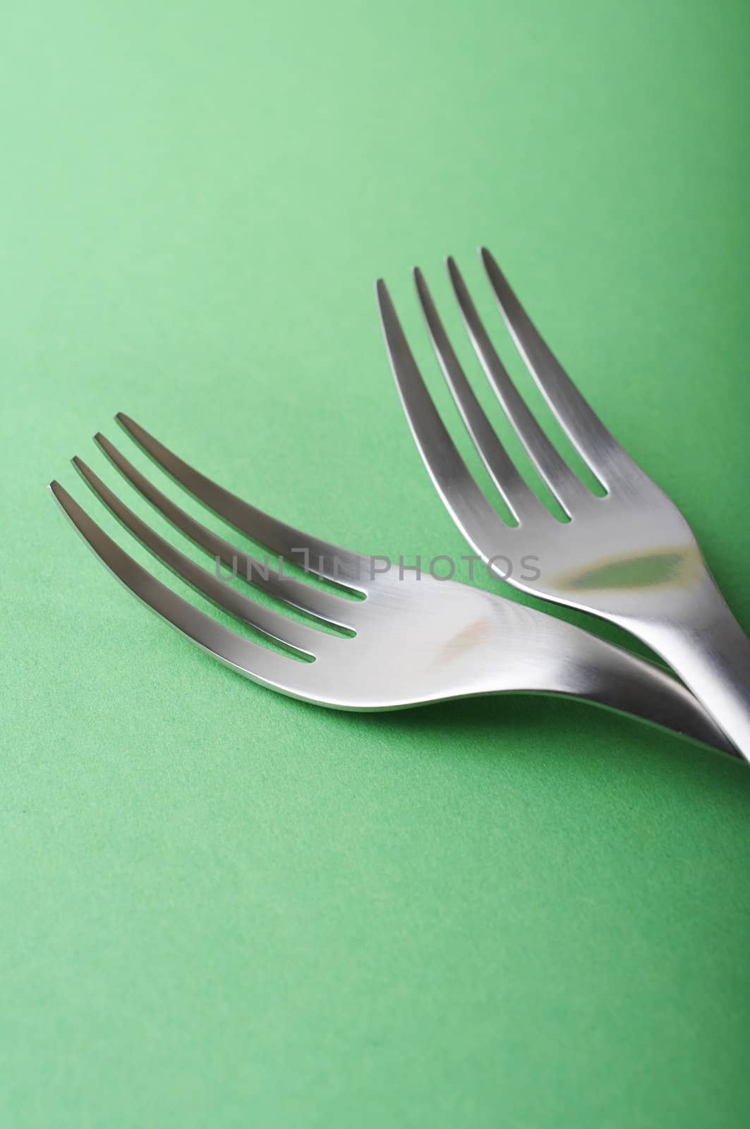 two forks head on green paper background