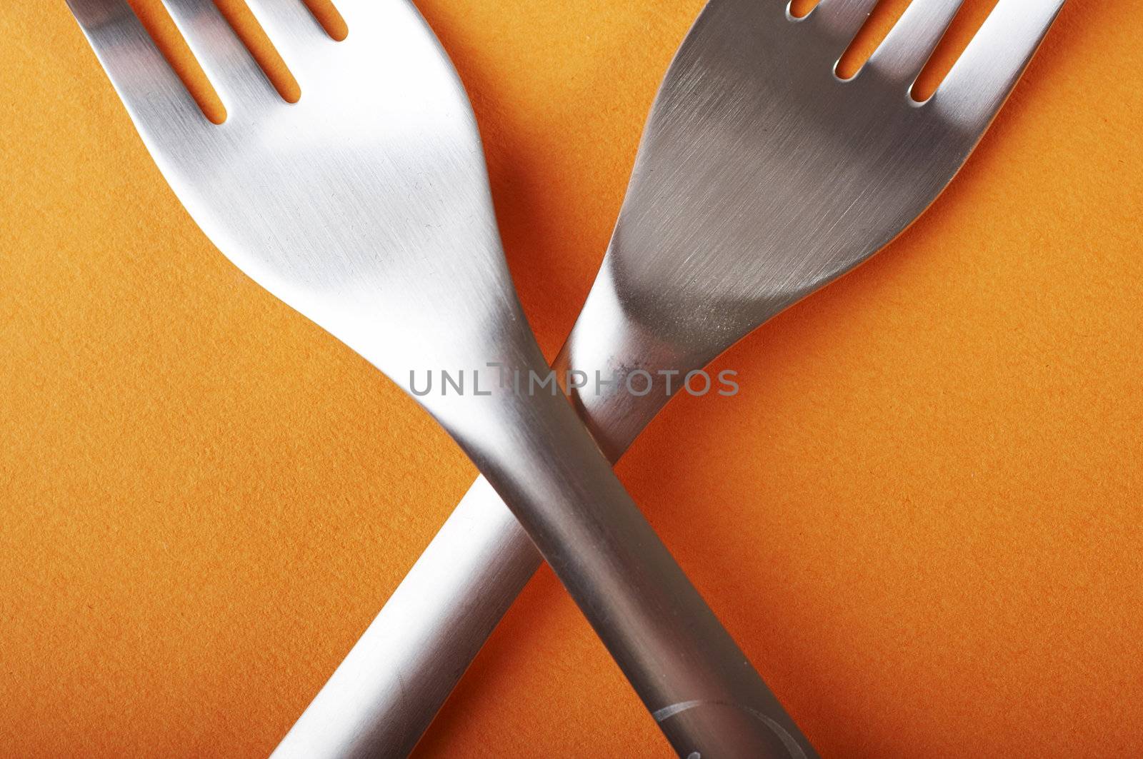 Two crossed forks over a orange background