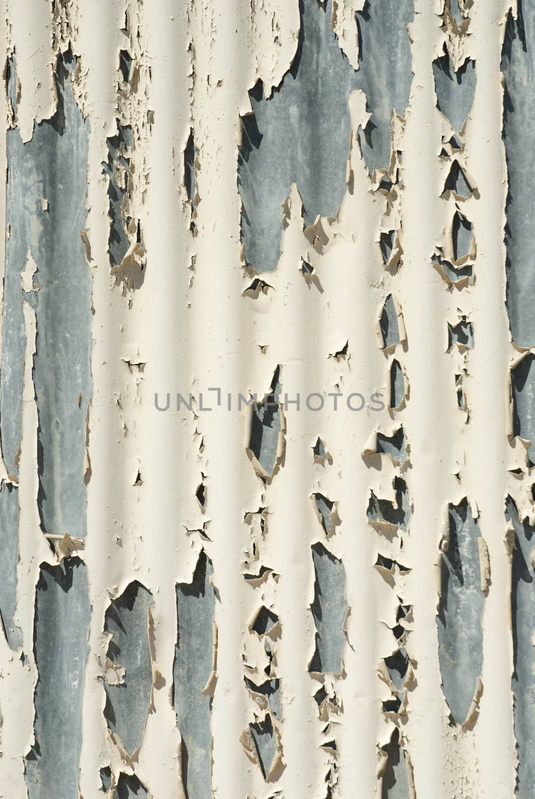 Peeling white paint from curved metal surface on the side of a building