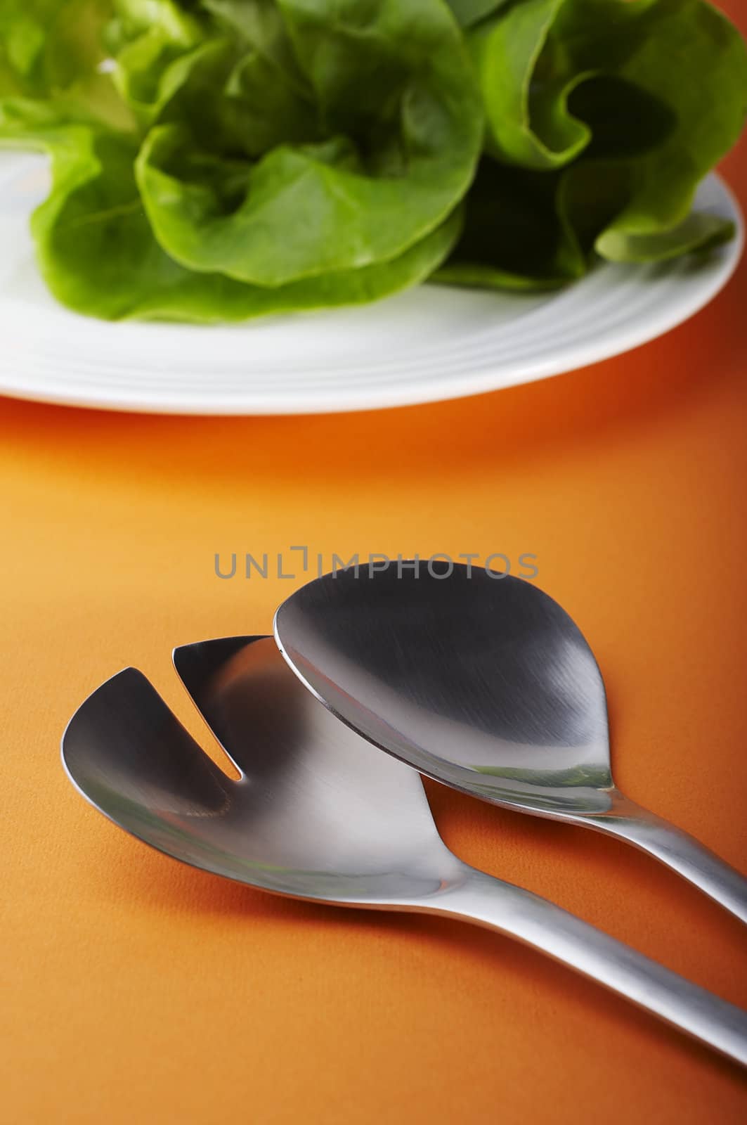 Salad spoon and fork on orange background 