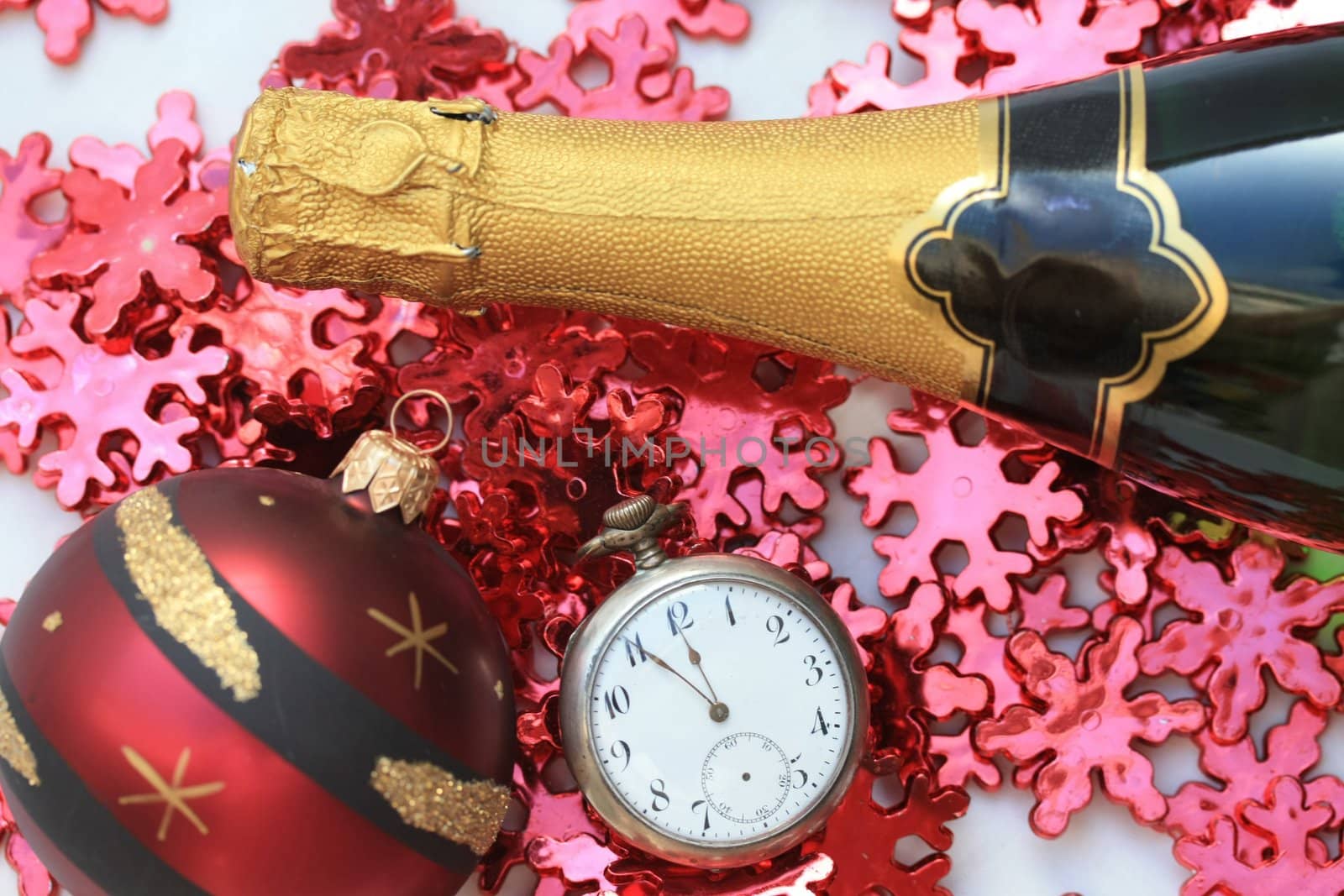 A bottle of champage with a pocket watch and red christmas decorations