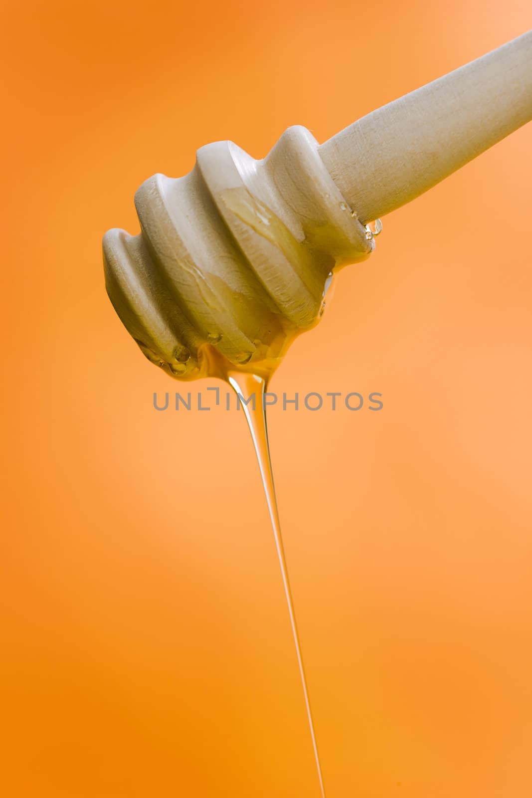 Wooden honey stick over a orange backgound