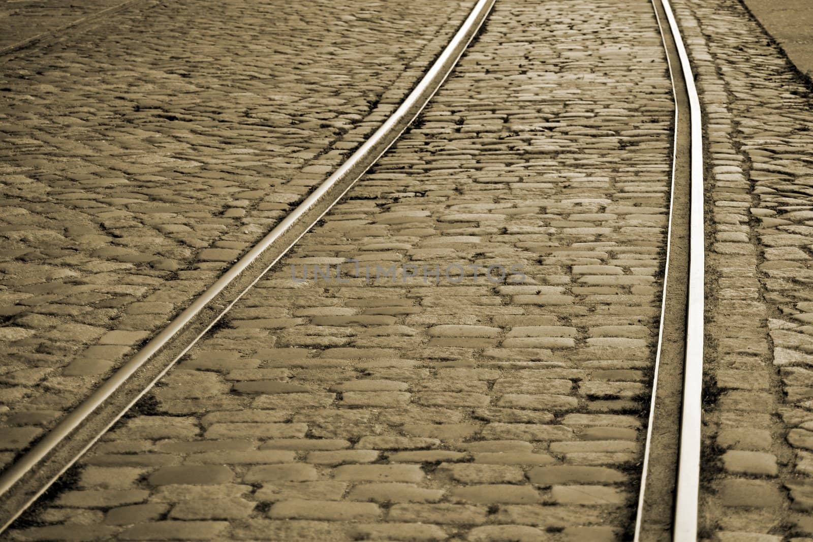 Railtracks in a very old cobblestone road in an abandoned industrial area. Sepia toned.