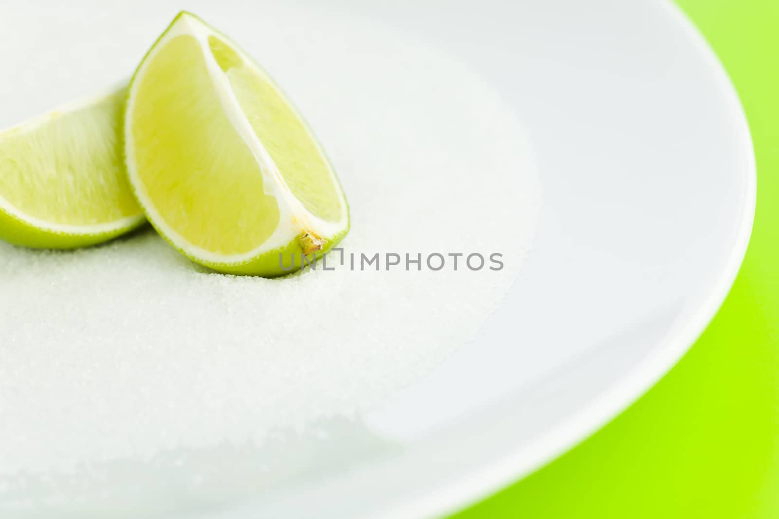 Lime halves top of the sugar on the plate