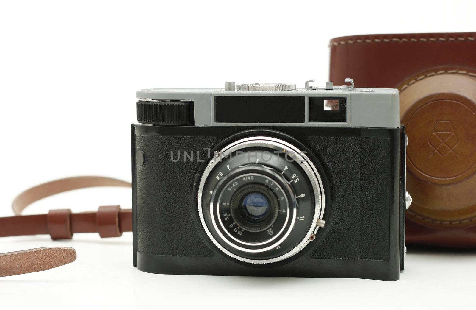 old antique analog photo camera isolated on white with authentic camera bag in background.