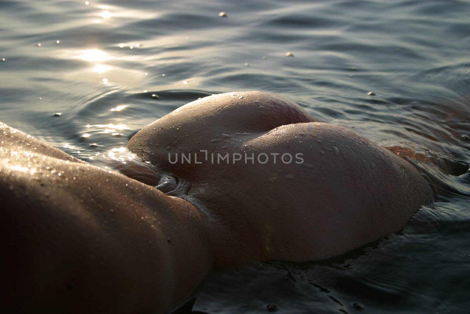 The woman with a beautiful body in water on a sunset