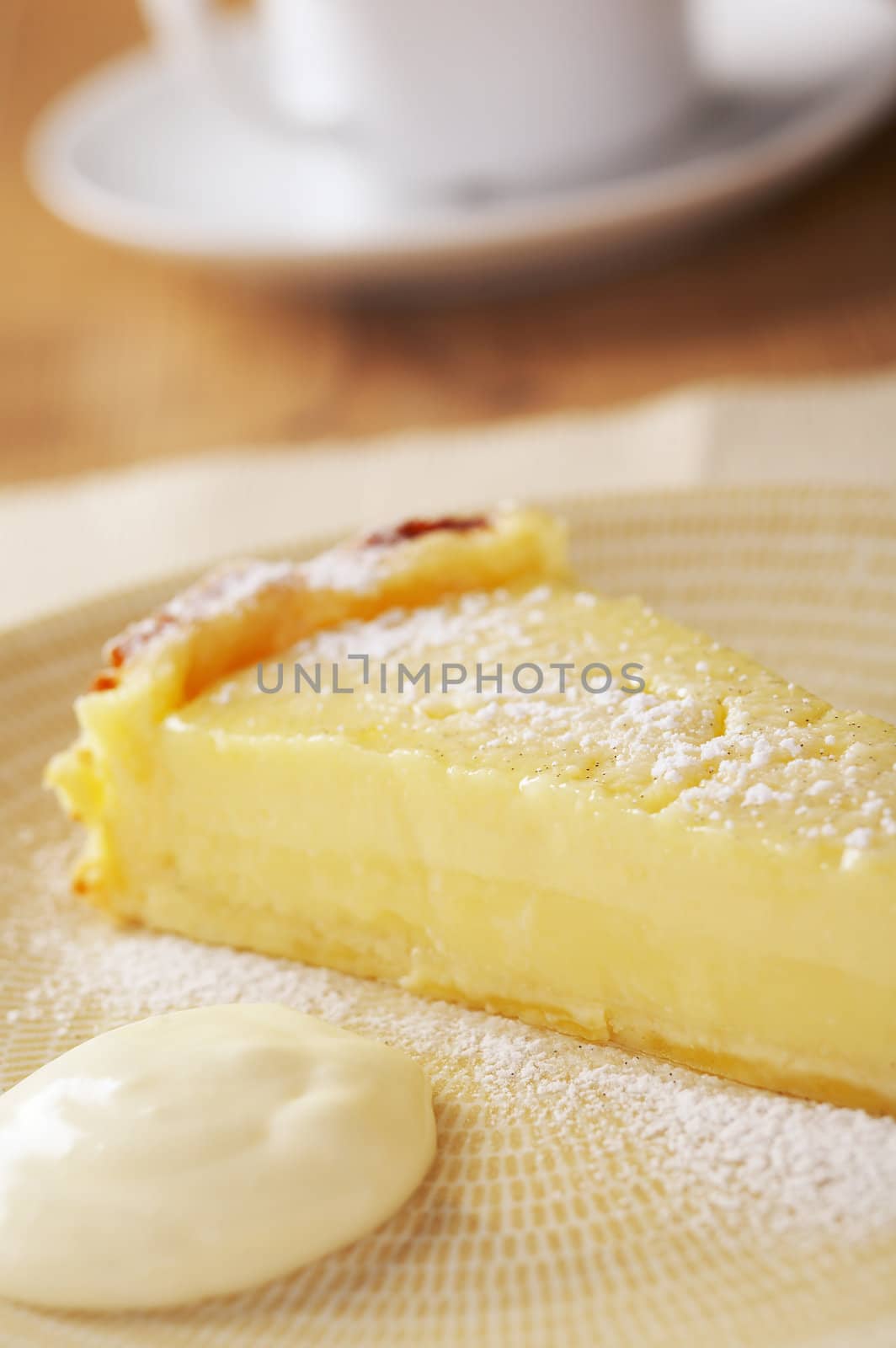 Home made icing sugar topped lime tart with cream on wooden the table