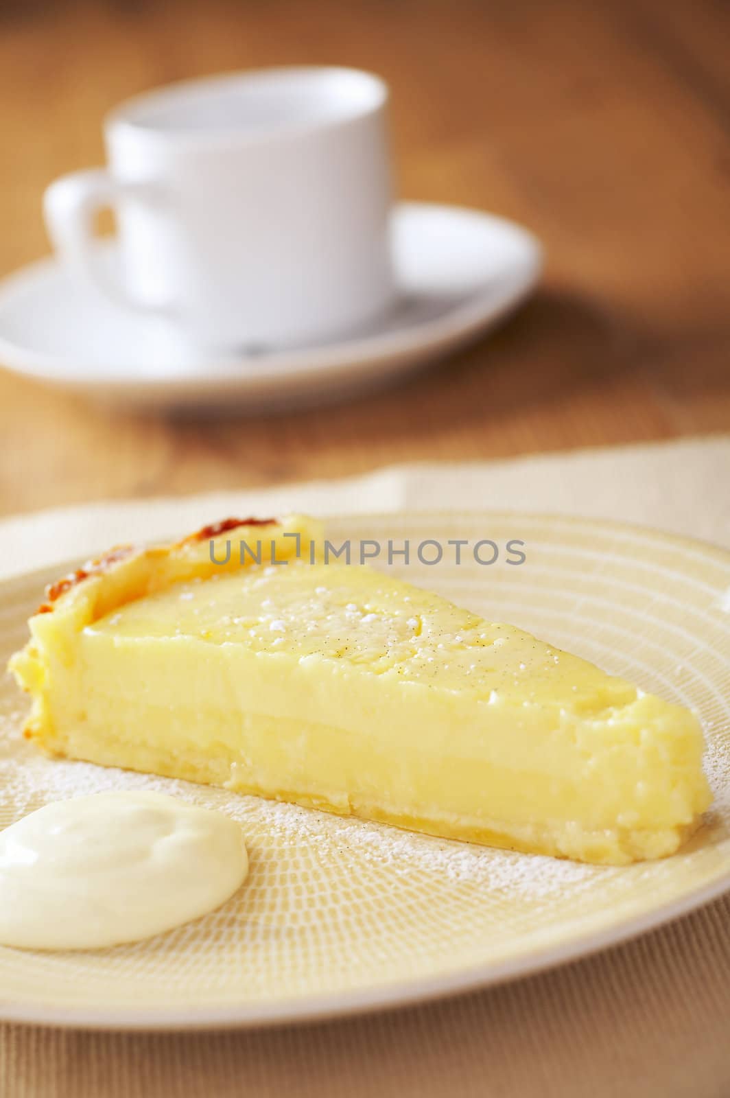 Home made icing sugar topped lime tart with cream on wooden table