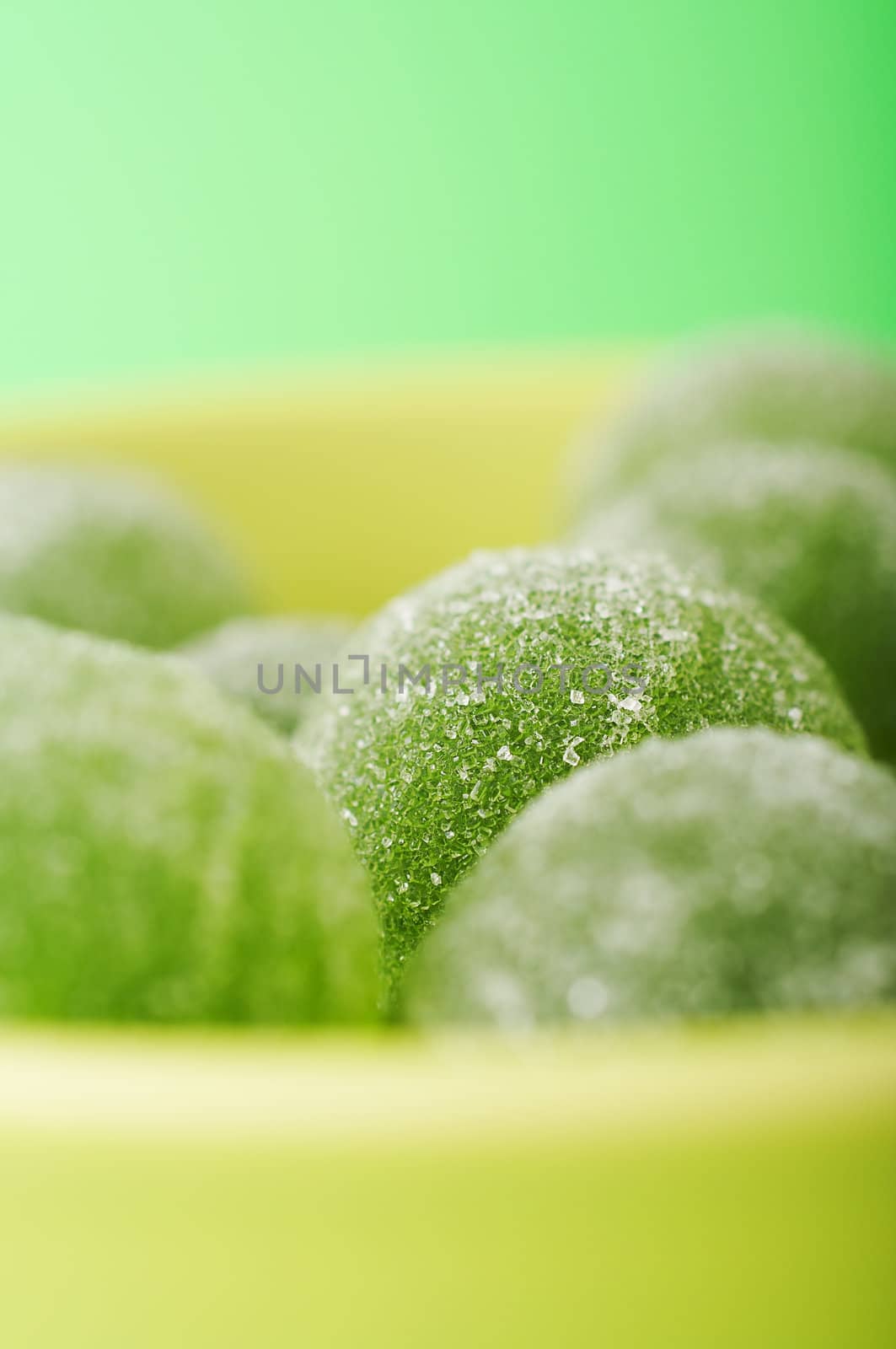 Green marmalade balls in the bowl on the green background