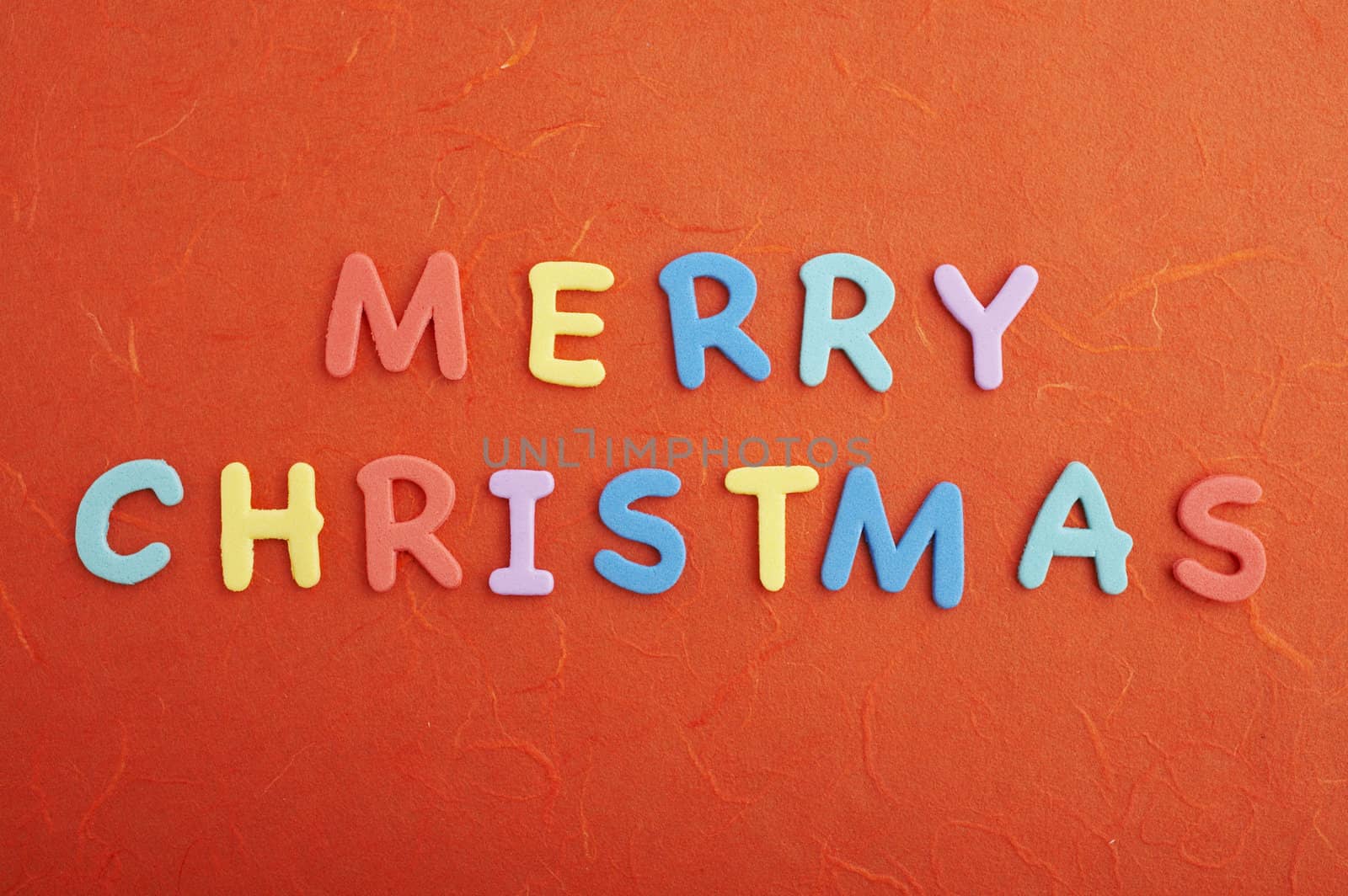 Merry christmas text (colorful soft rubber letters) on red silk paper