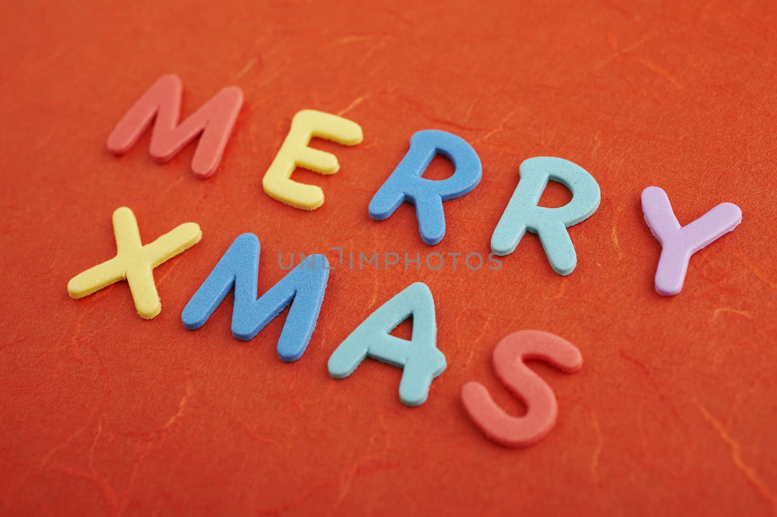 Merry christmas text (colorful soft rubber letters) on red silk paper