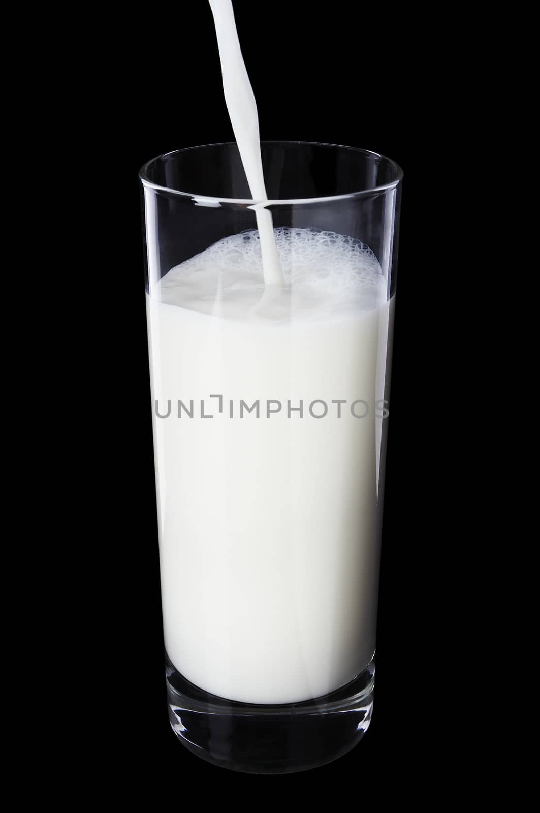 Pouring milk in the glass on black background