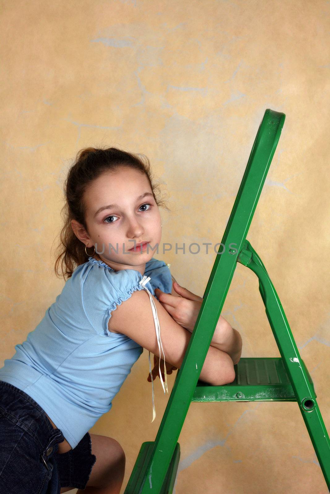 Portrait of the young girl with step-ladder on a yellow background
