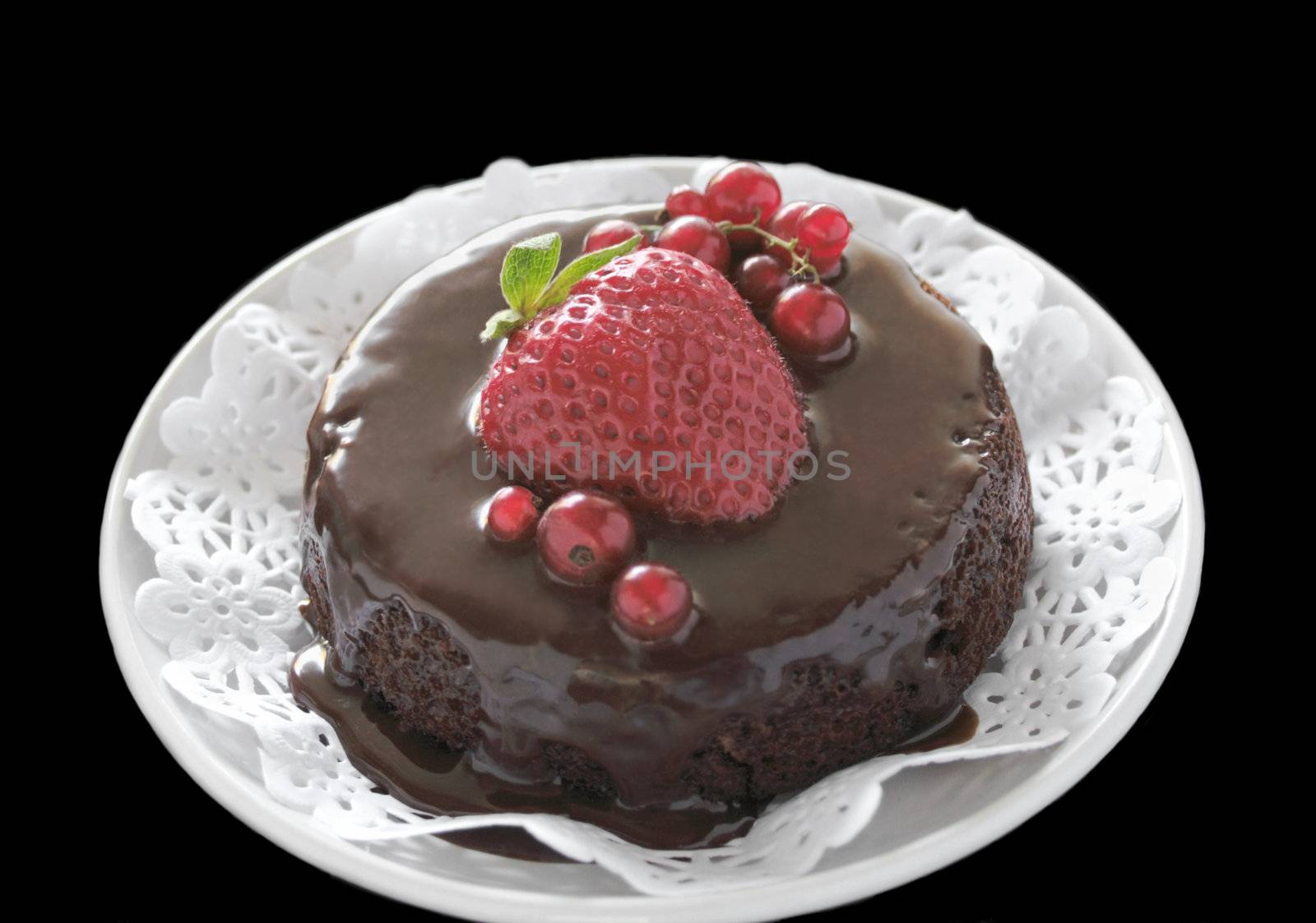 individual-sized chocolate cake topped with ganache, a strawberry and red currants