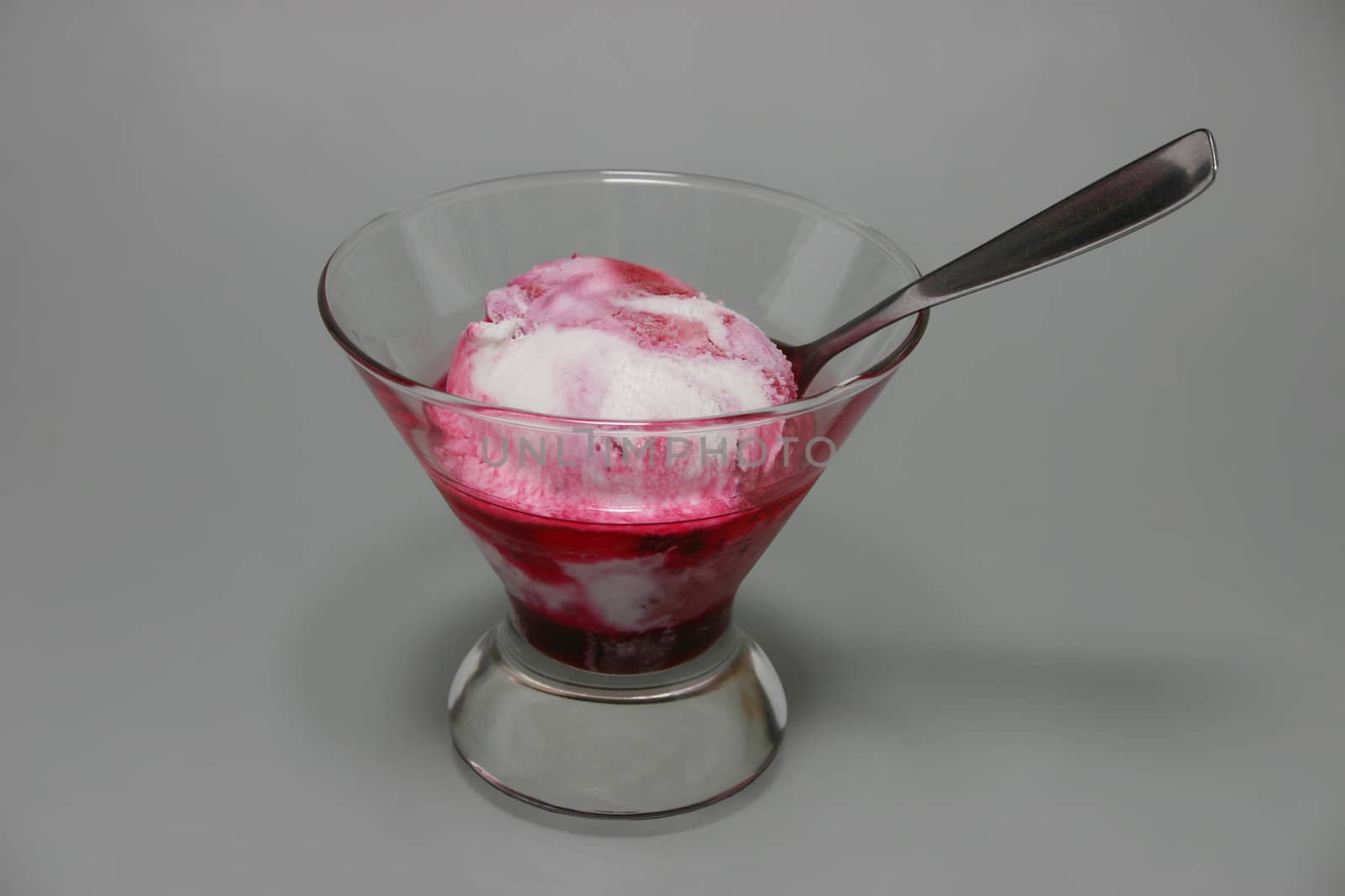Ice cream with berry jam on grey background.
