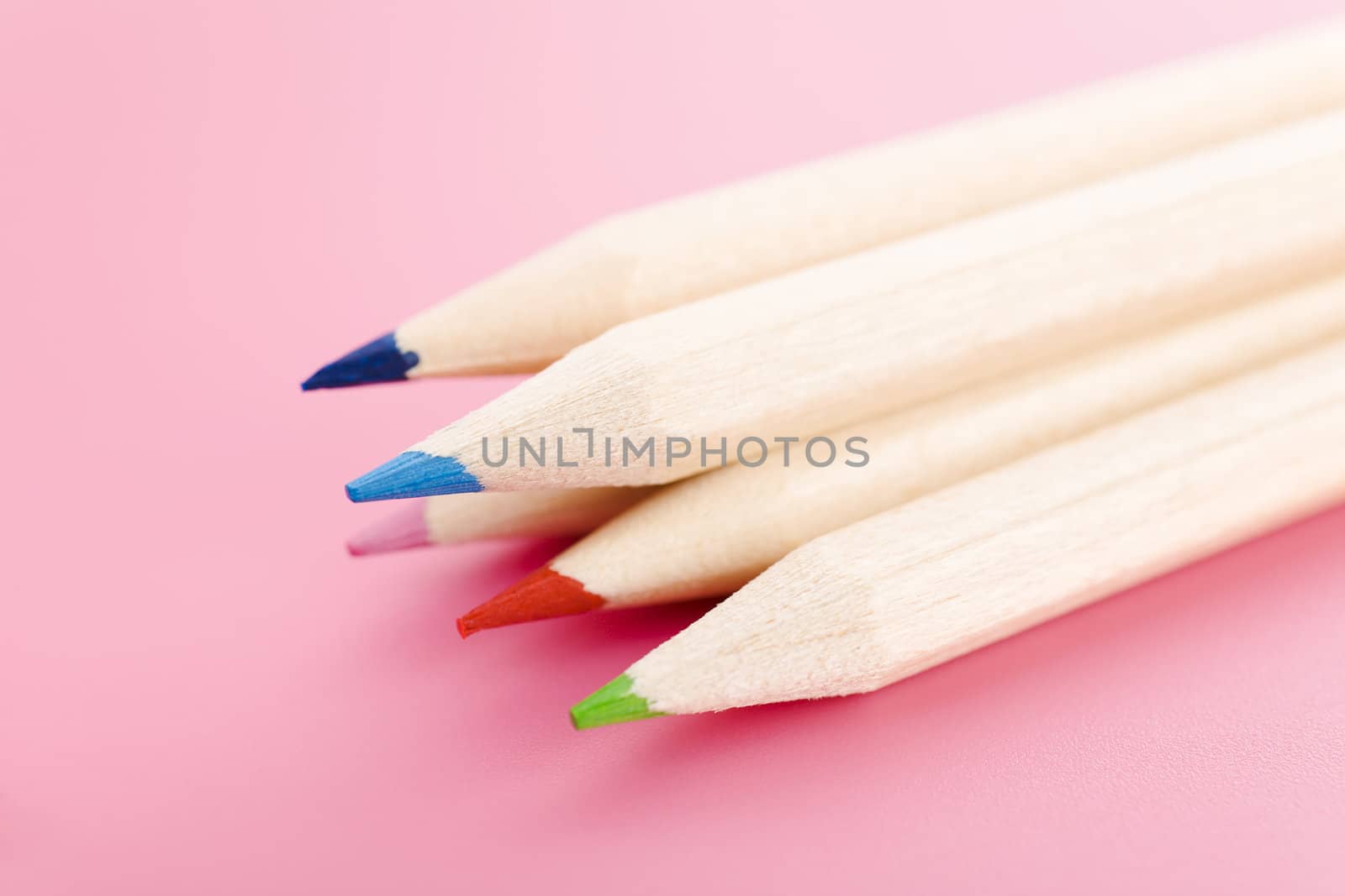 Pile of wooden pencils over a light red background