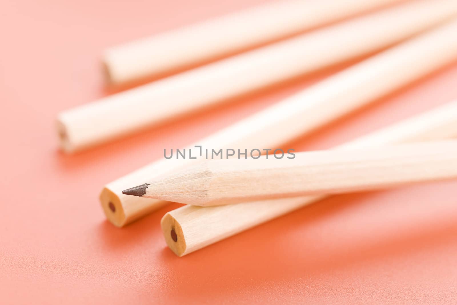 Pile of wooden pencils over a light red background