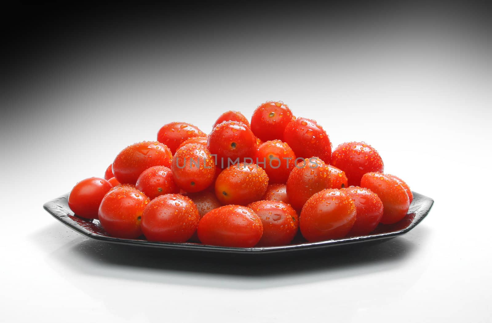 Lot of cherry tomatoes with drops over a black plate. Look at my gallery for more fresh fruits and vegetables.