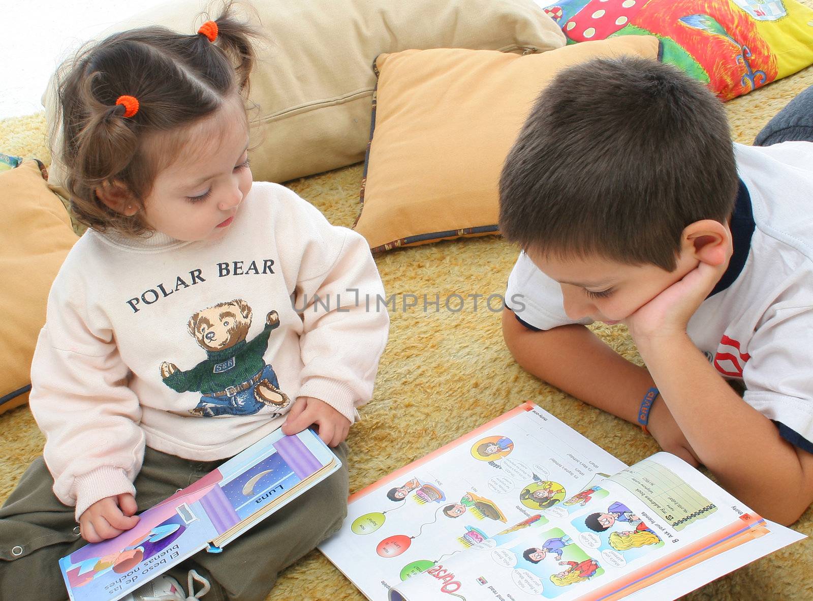 Brother and sister reading books over a carpet. They look interested and concentrated. Visit my gallery for more images of children
