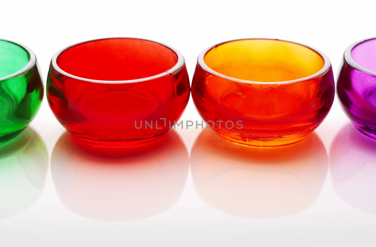 Four colored cups on white reflective background