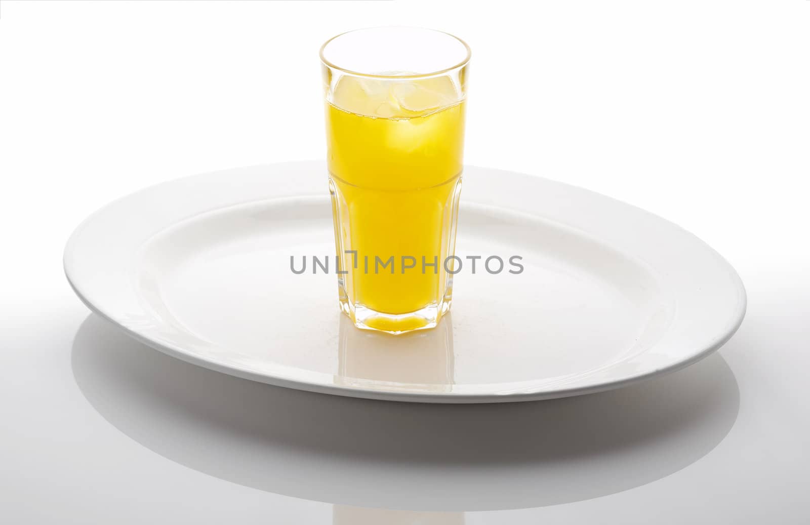 Glass of yellow lemonade on the white plate