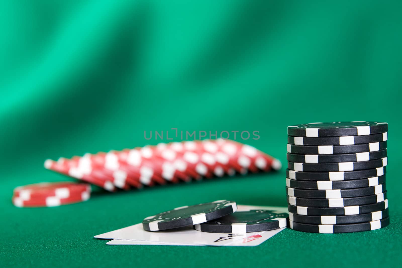 Stack of chips and two aces on green linen background