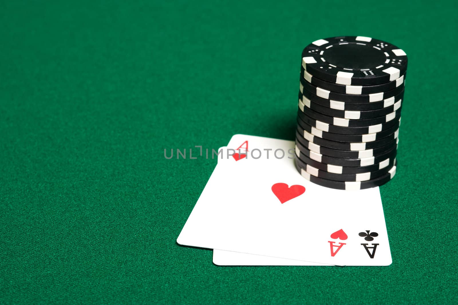 Stack of chips and two aces on green linen background