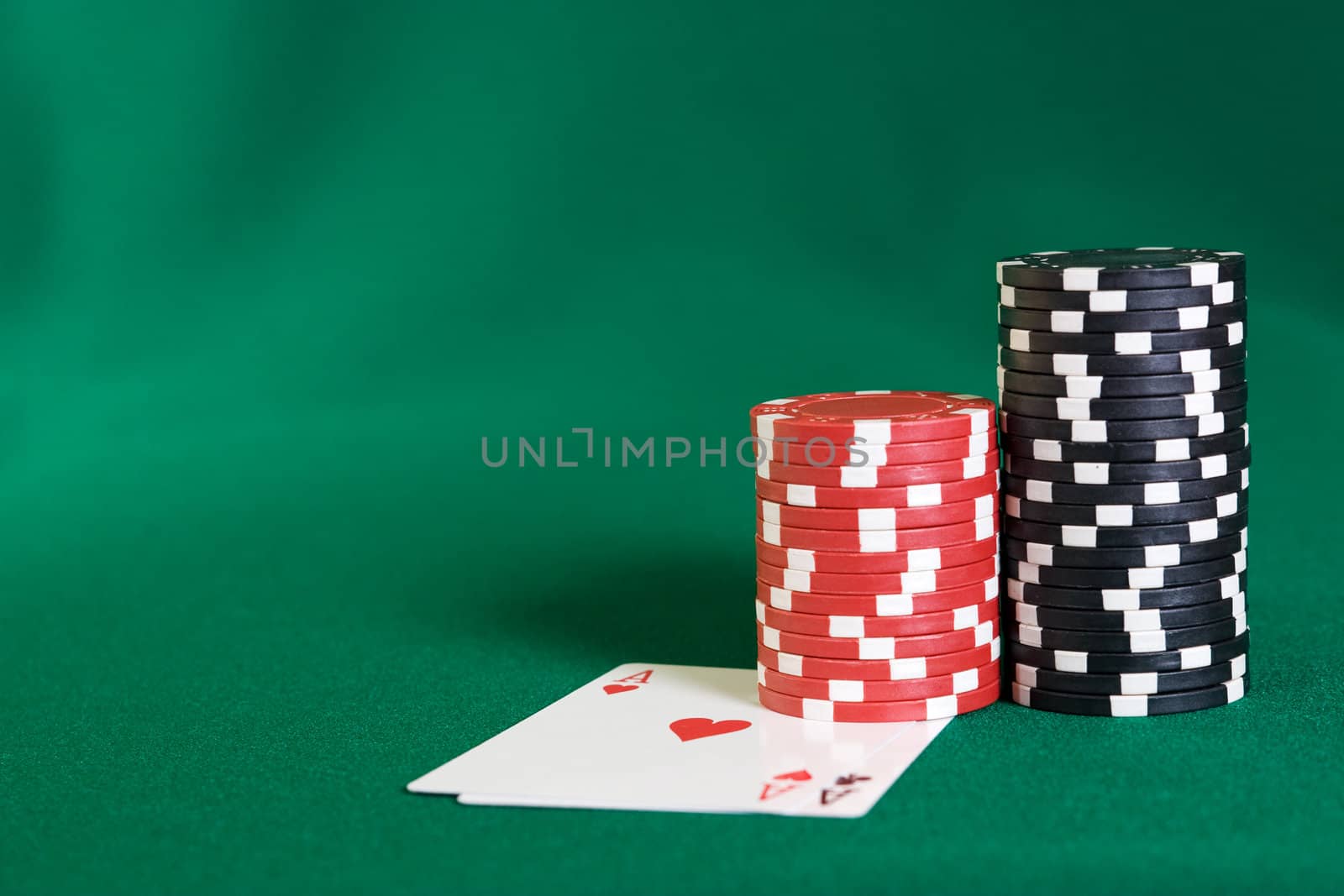 Stack of chips and two aces on green linen background