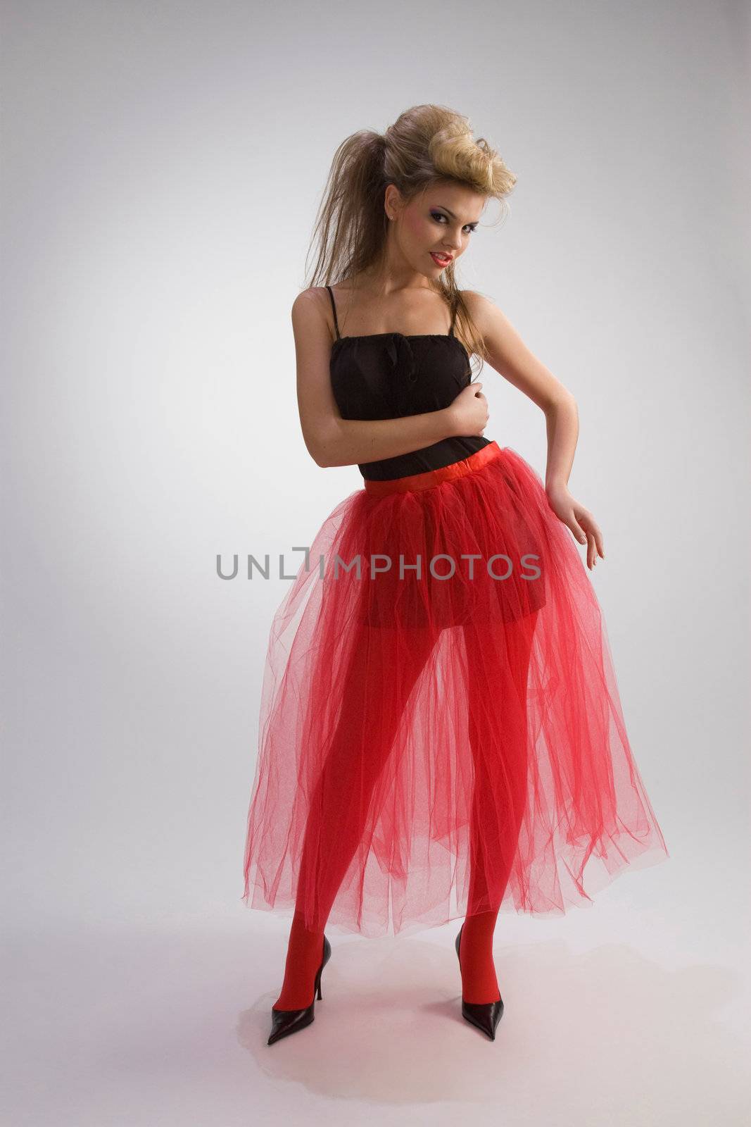 Beautiful woman in red diaphanous skirt on grey background