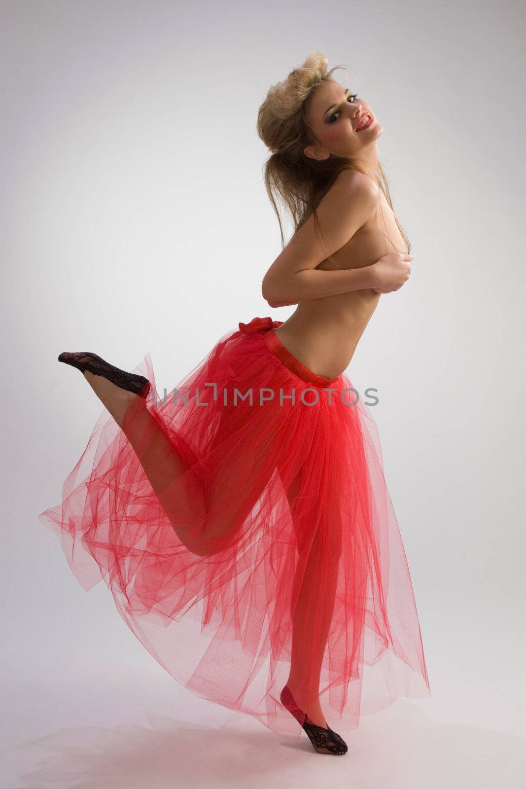 Beautiful woman in red diaphanous skirt dancing on grey background