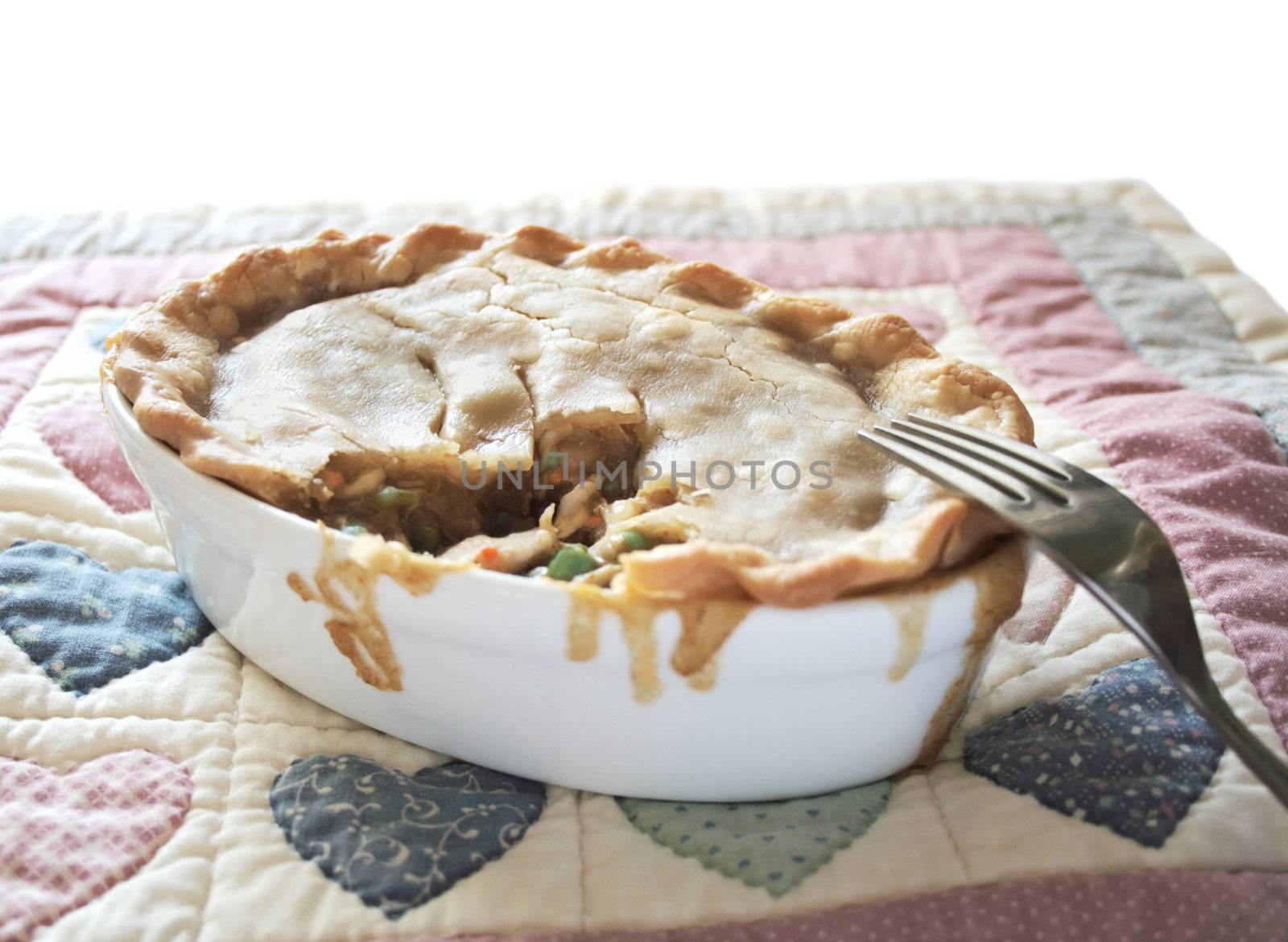 a chicken potpie in an individual casserole dish on a quilted place mat with calico hearts