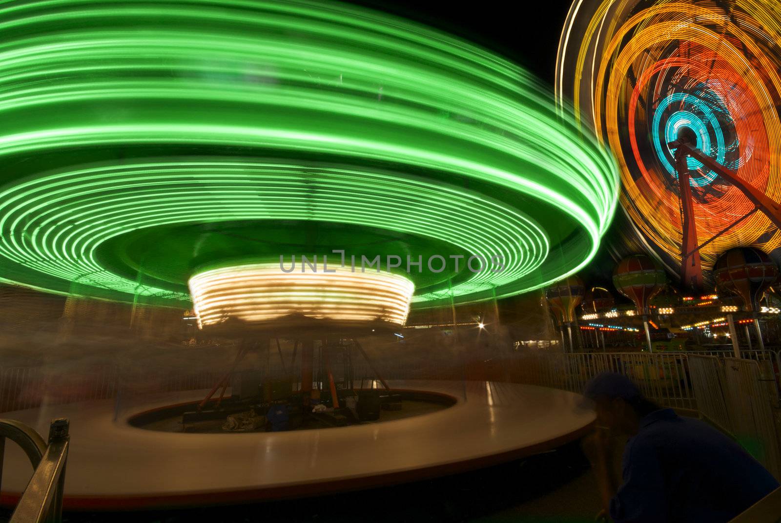Two whirling carnival rides create magical and colorful rings of light in the night