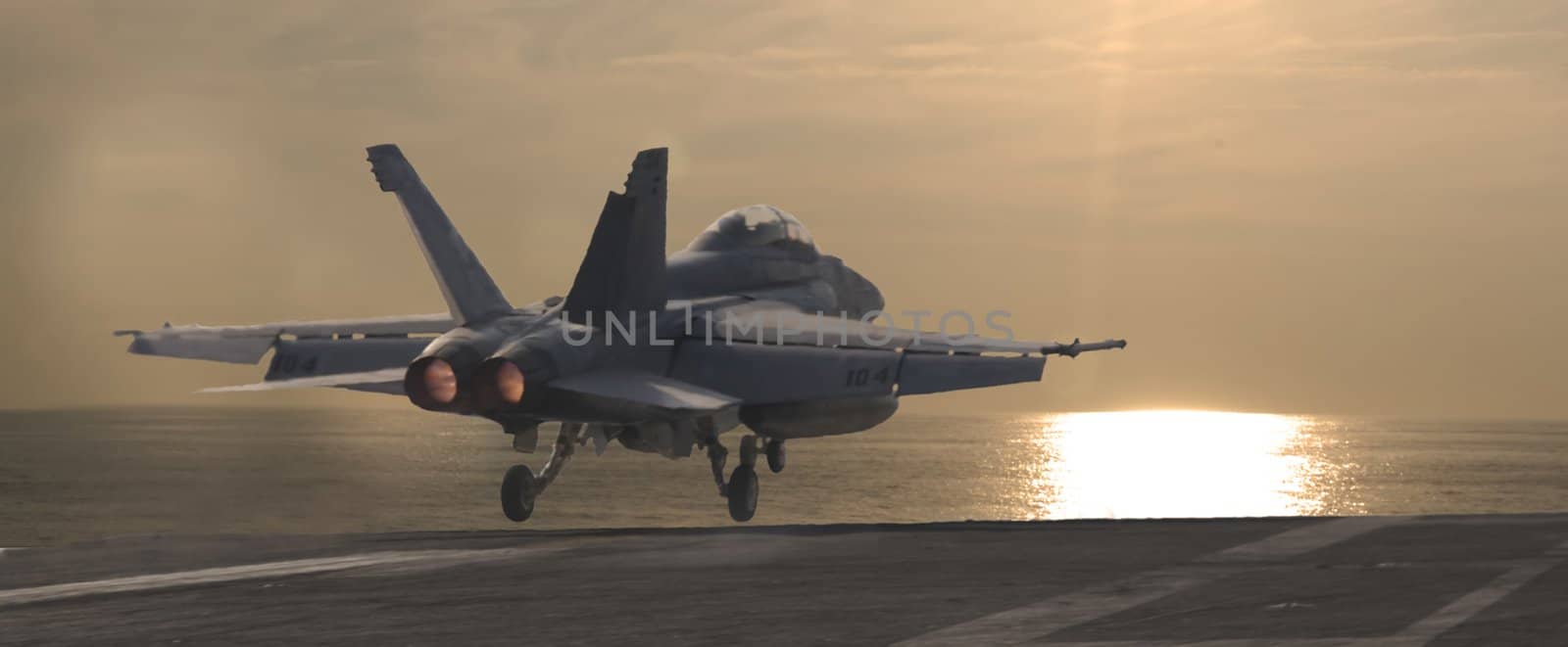 An F-18 Super Hornet is launched from a nuclear powered aircraft carrier at sunset