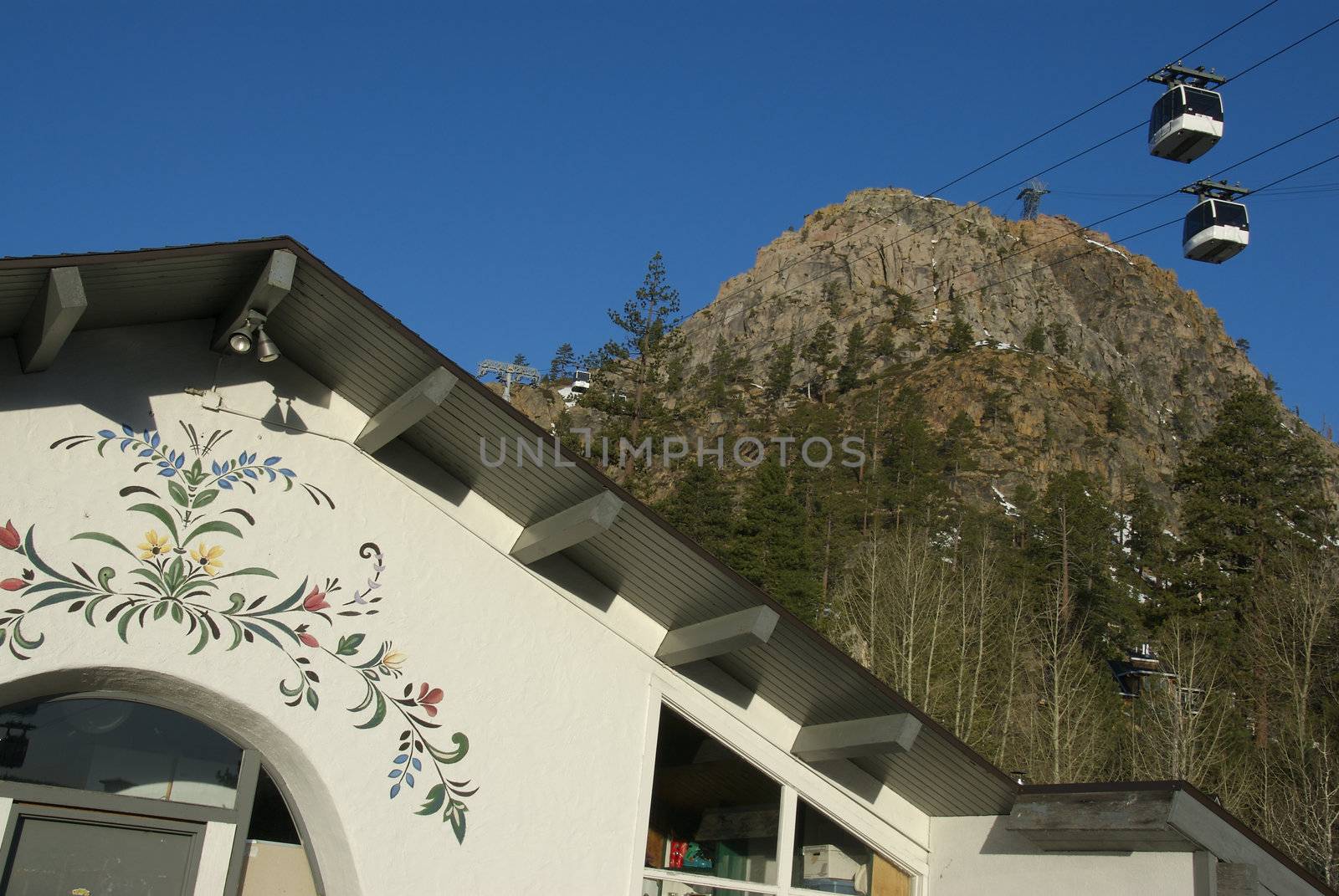 A Scenic ski lodge sits against a tall mountain peak and gondola