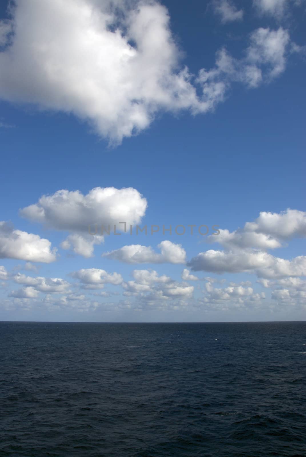 A beautiful blue sky over a calm sea with white clouds