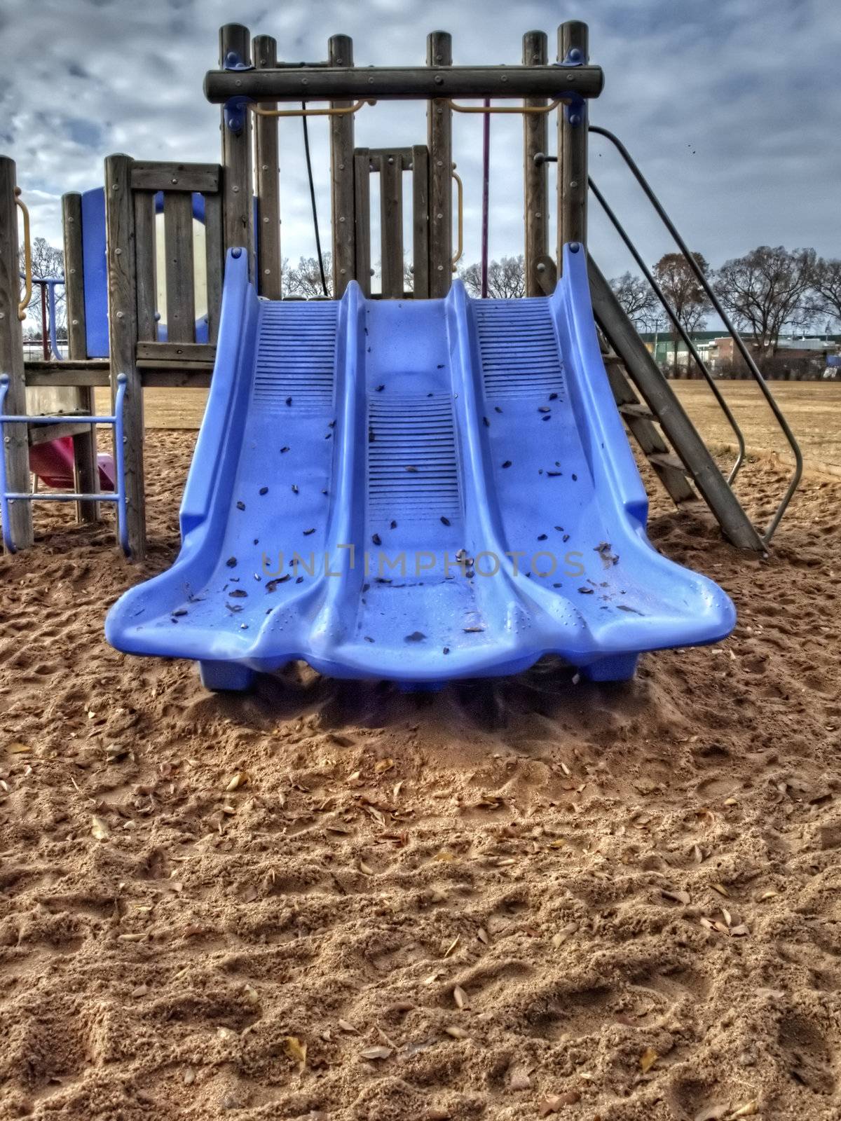 Three, connected blue slides on a playground in late fall.