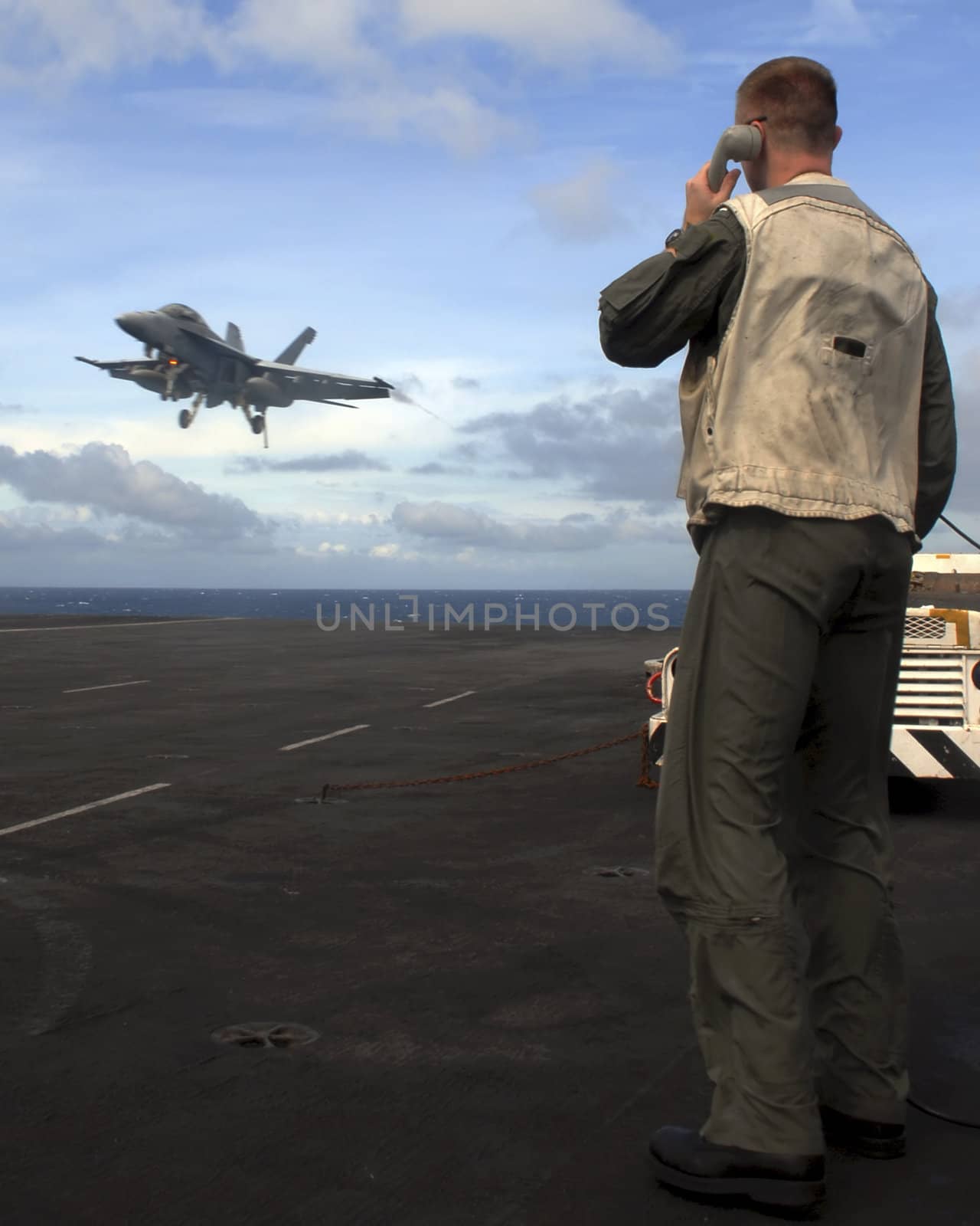 A Landing Signal Officer guides an F-18 Super Hornet aboard an aircraft carrier