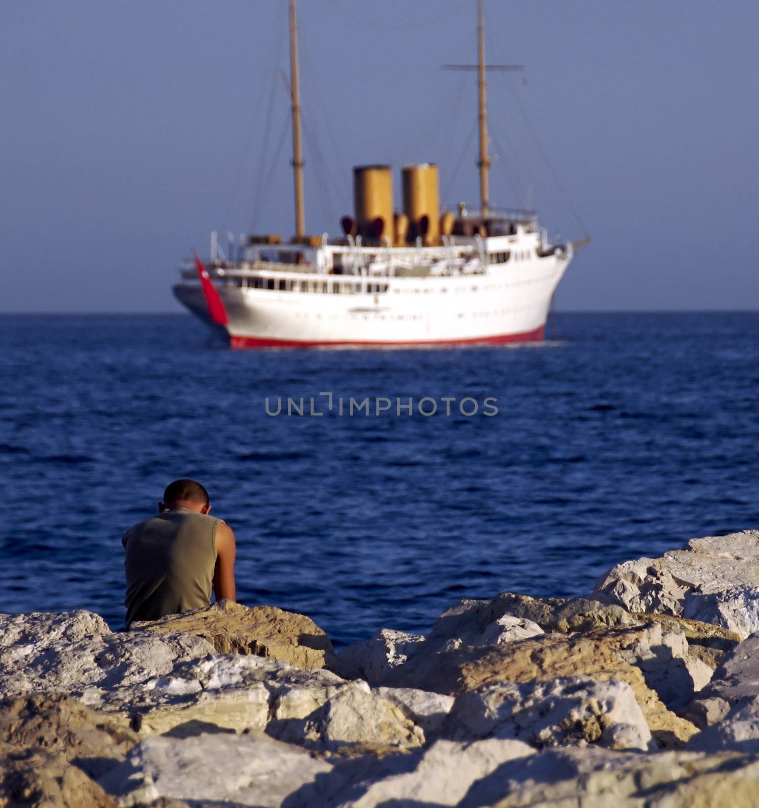 A lonely boy looks out at a departing ship