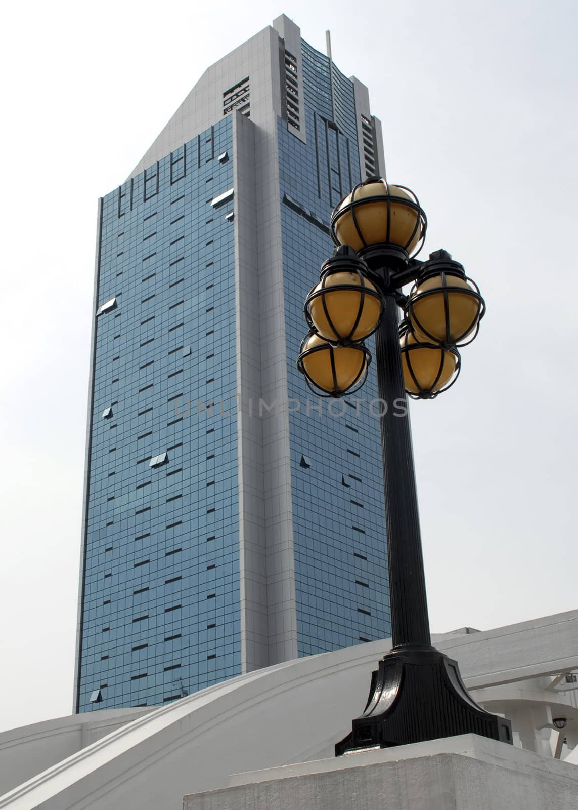 A modern business building is contrasted against a victorian era lamppost