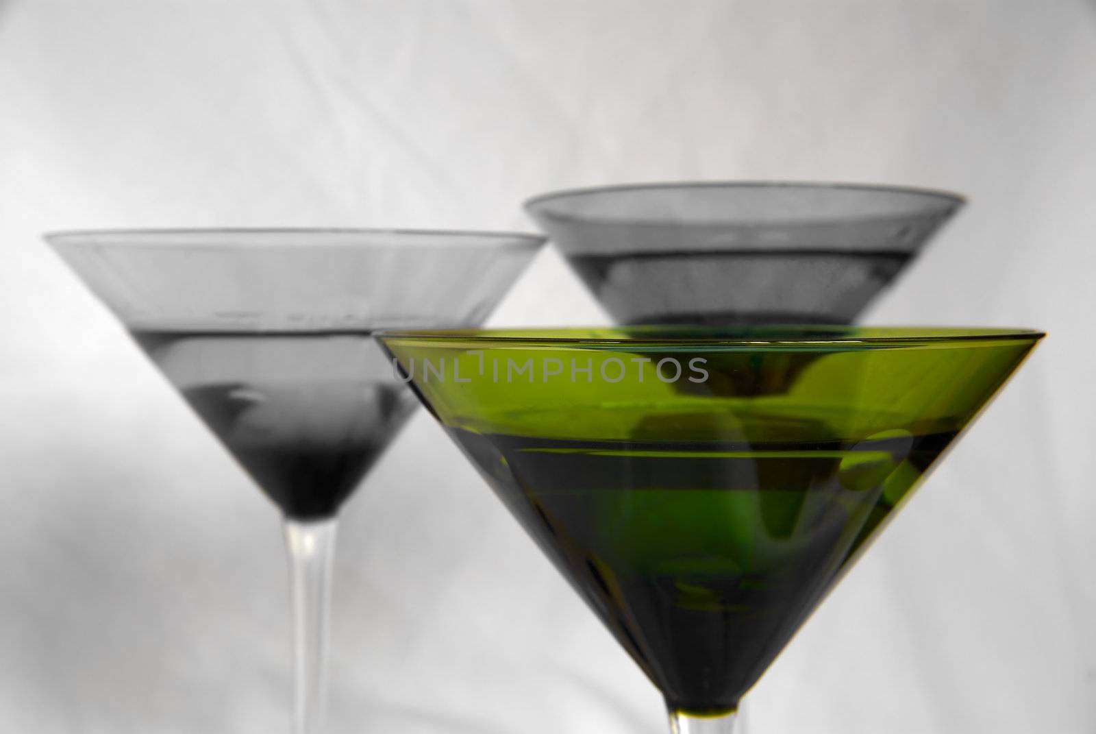 A green martini glass against two muted glasses in the background