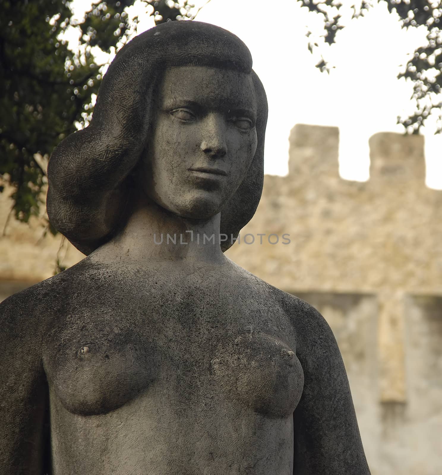 A medieval female statue adorns the grounds outside of a Portuguese castle