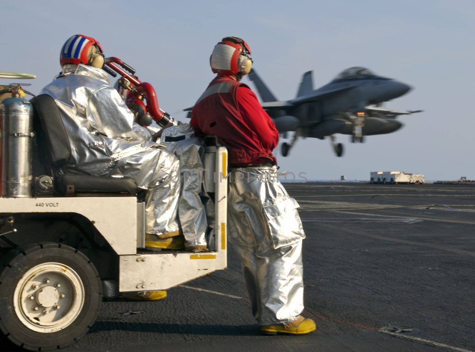 Sailors assigned to the "crash crew" watch as a Super Hornet lands aboard a nuclear powered aircraft carrier