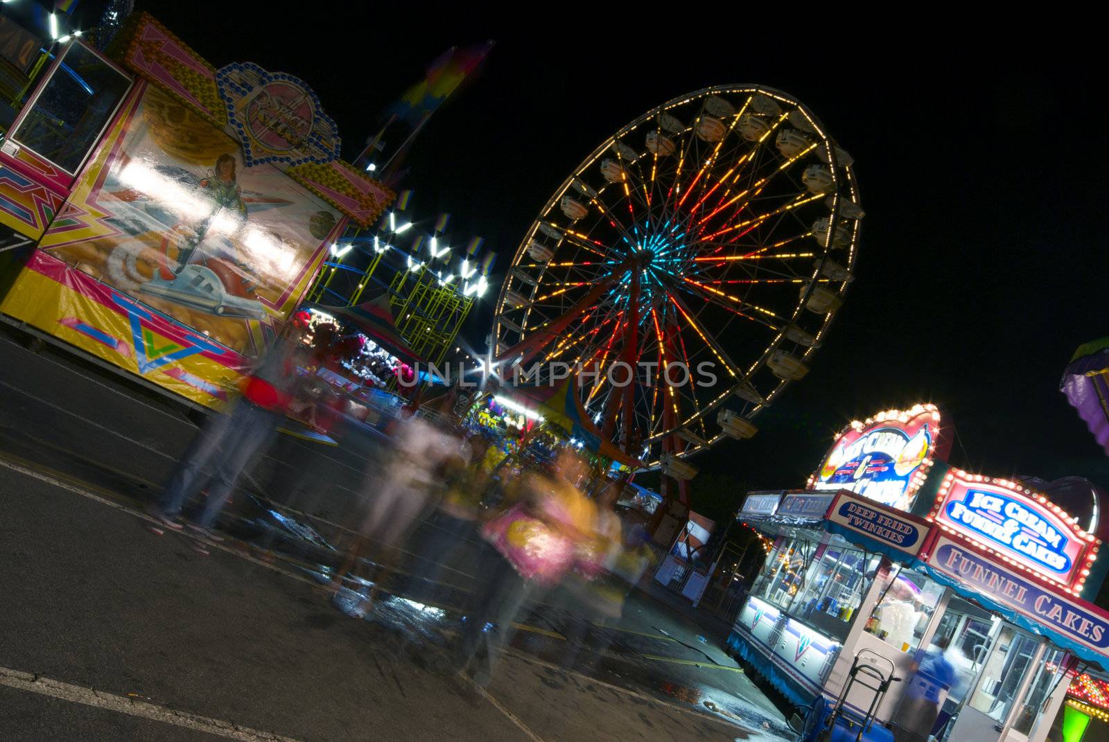 A group of friends wanders through a colorful carnival at night