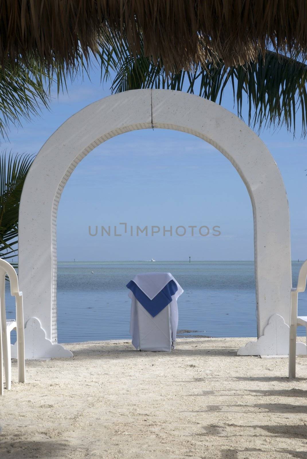 An altar and arch sit on a warm tropical beach before a wedding