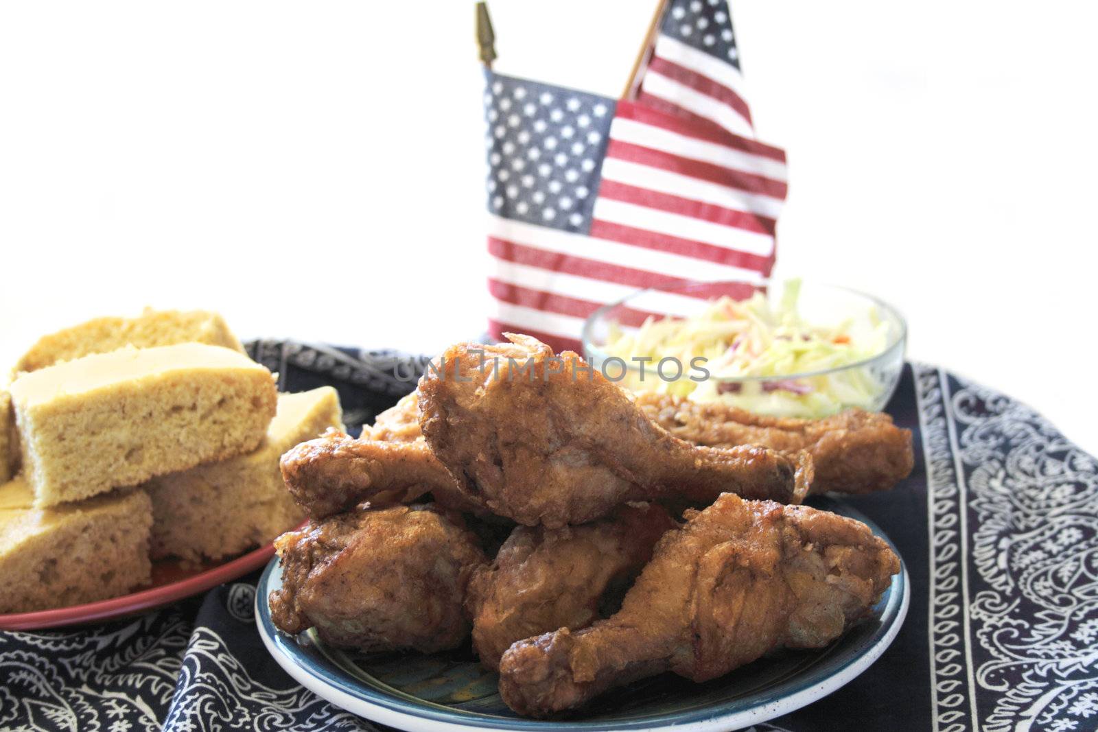 fried chicken legs, cornbread, and coleslaw on a dark blue bandana for a holiday picnic