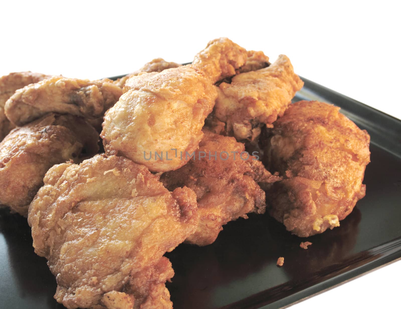 golden fried chicken on a black tray isolated on white